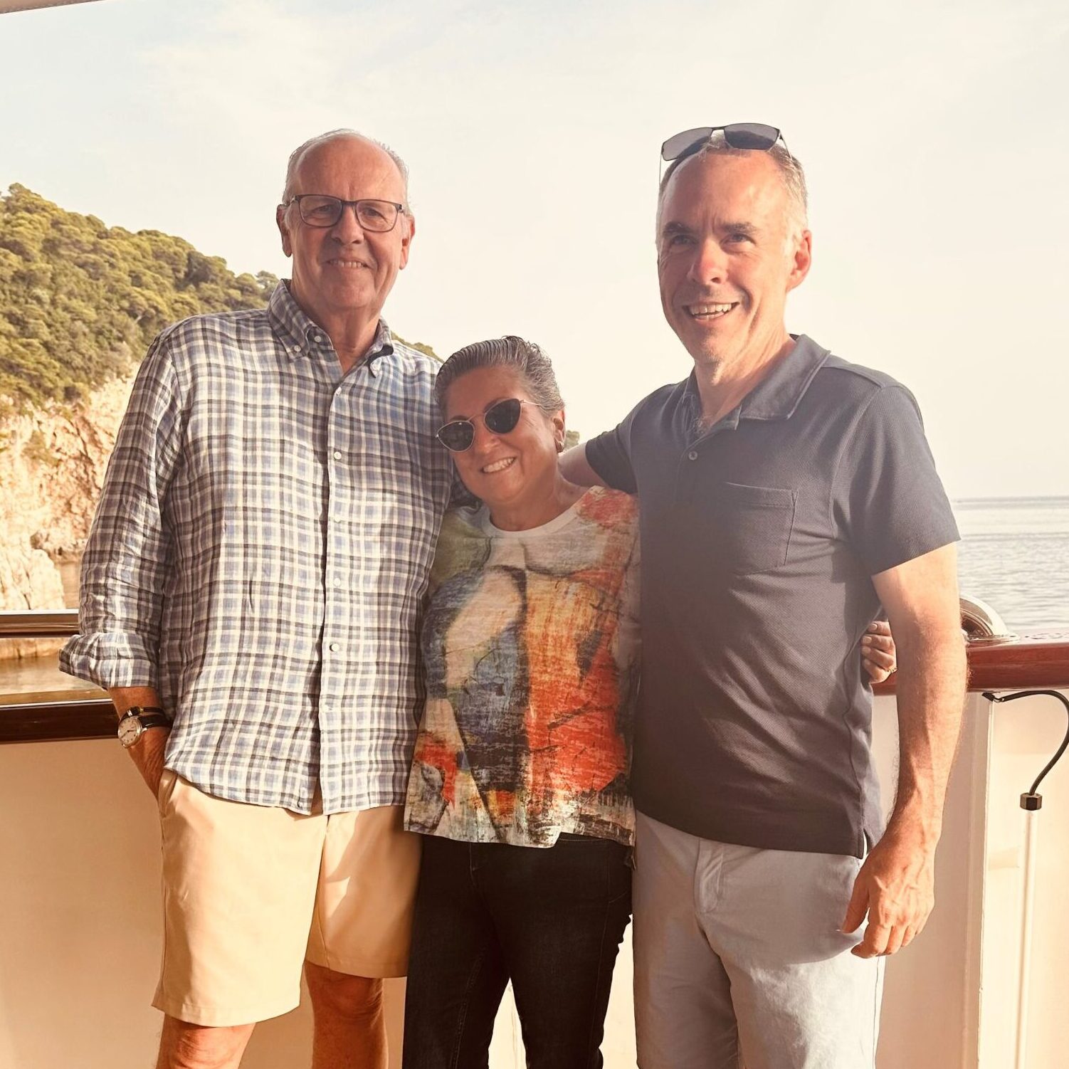 three people pose on the deck of a ship